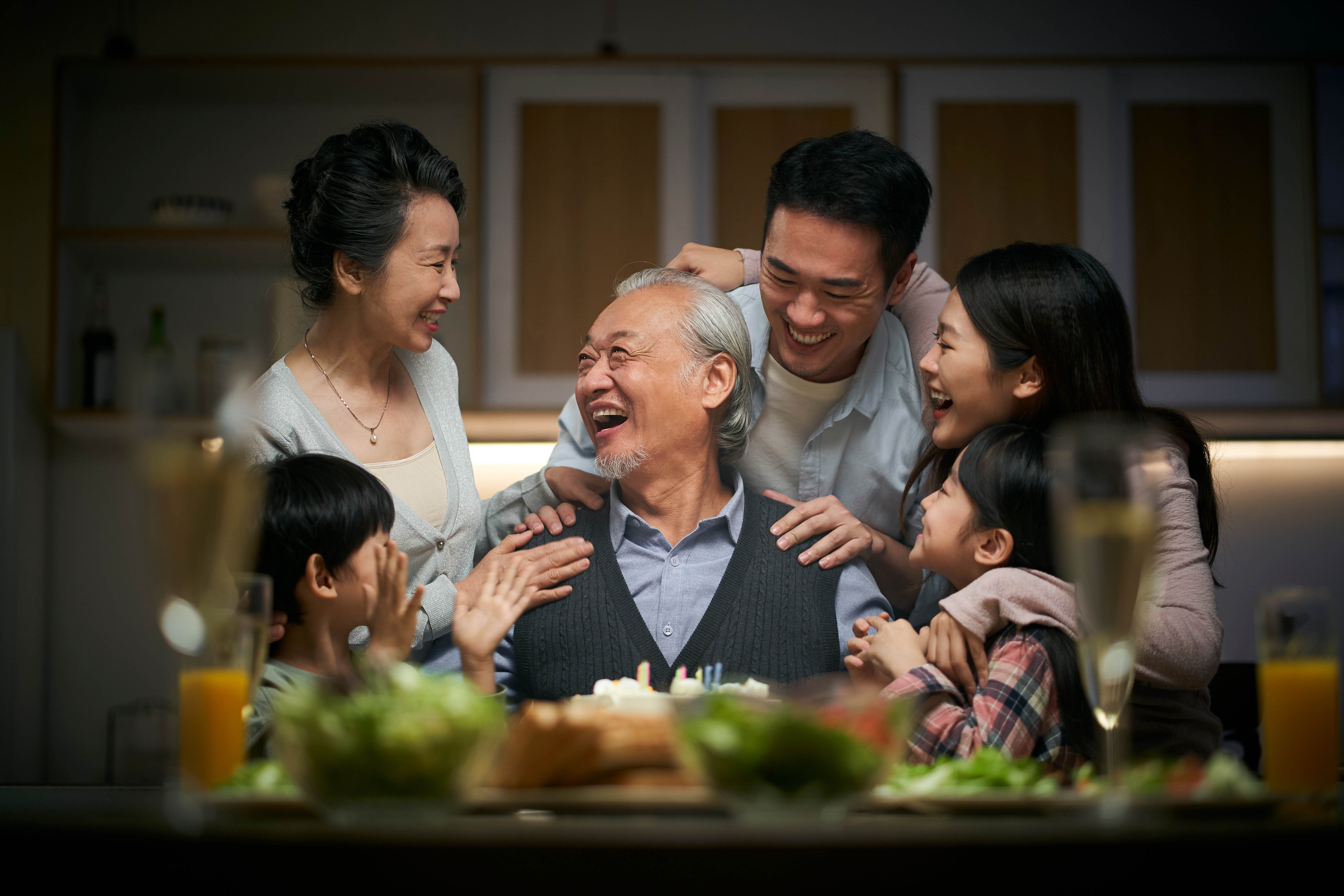 Asian family, centered around the grandfather with his daughter, her children, and two young children around